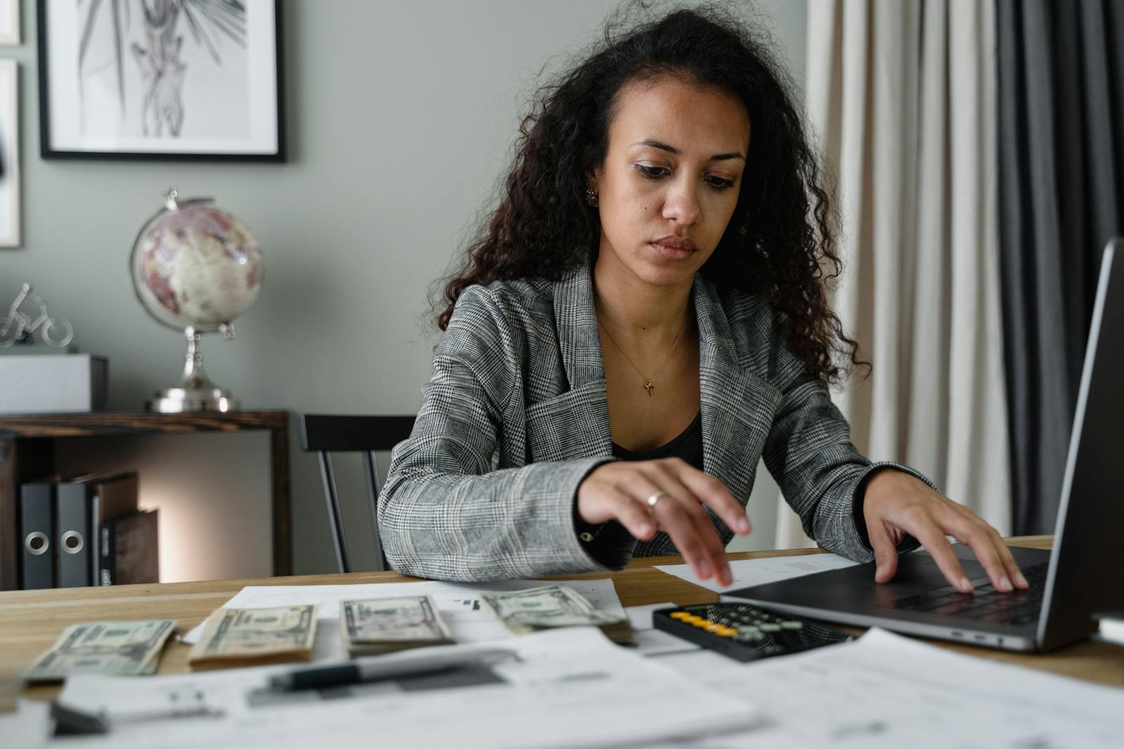 Femme professionnelle analysant des documents financiers et comptant de l'argent au bureau.