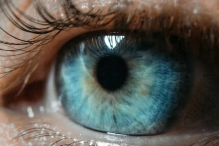Gros plan macro d'un œil humain présentant un iris bleu et des cils détaillés.