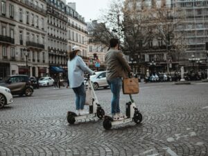 homme en chemise blanche et jean bleu tenant un chariot noir et rouge près de lui