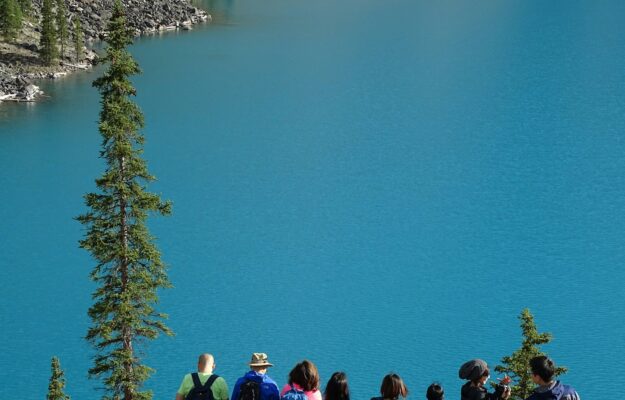 des gens assis sur le bord d'un rocher face à un plan d'eau